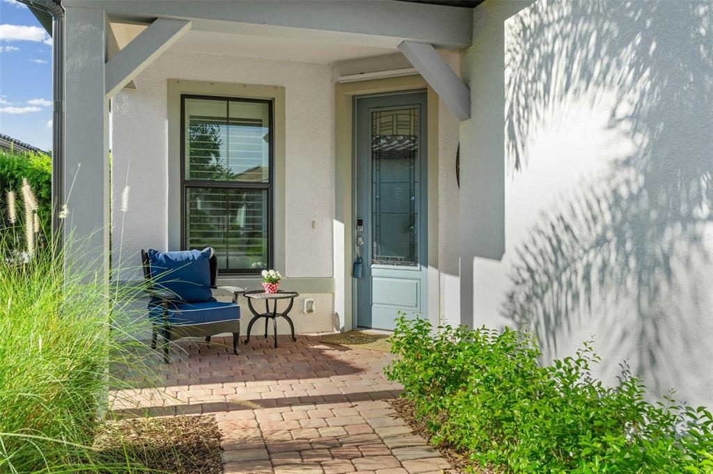 A covered front porch features a blue armchair, a small table, and a glass-paneled door — 17726 NORTHWOOD PLACE, BRADENTON, FL