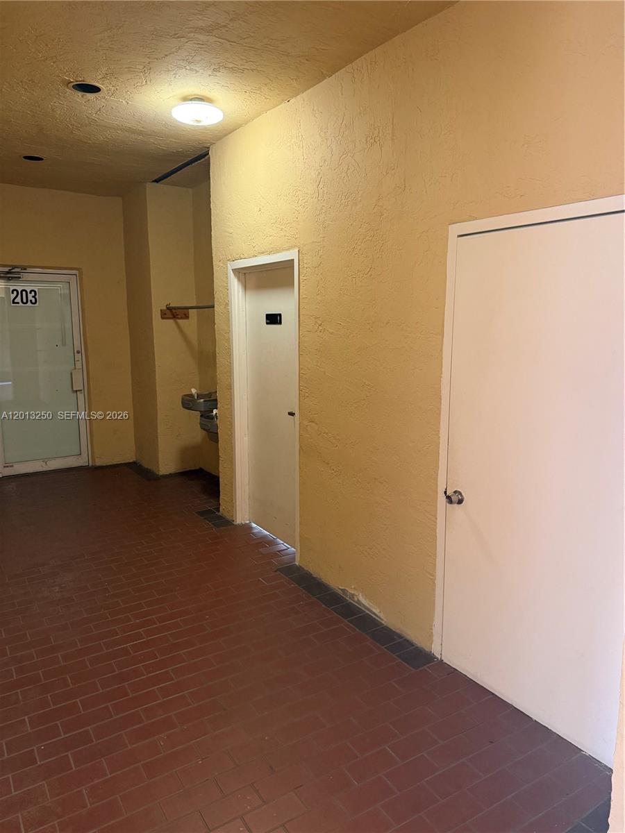 A hallway with red brick flooring features a door labeled 203 and two additional doors — 7400 NW 7th St # 201, Miami FL 33126, MIAMI, FL