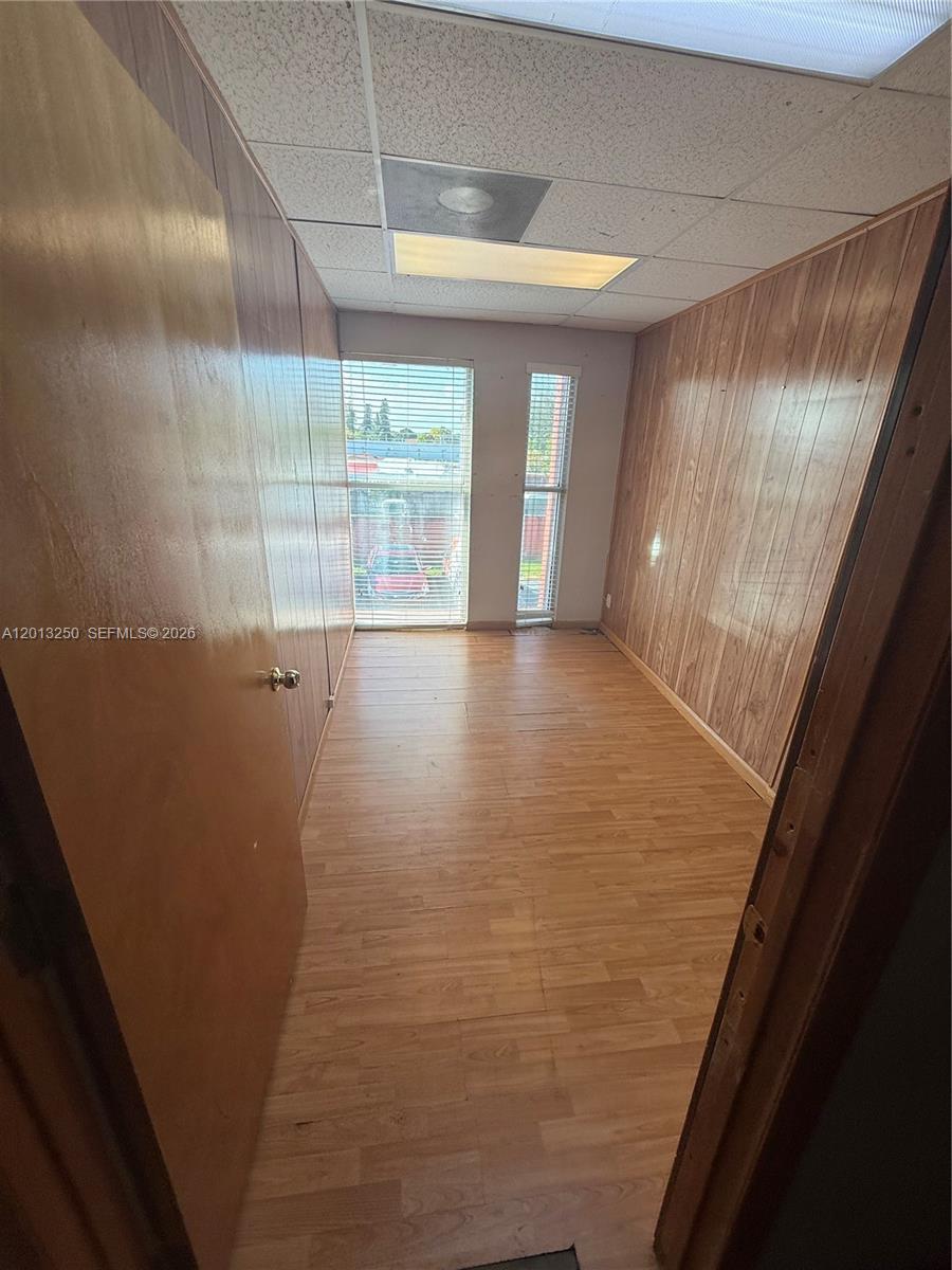 A narrow room features wood-paneled walls, light wood-look flooring, and a drop ceiling — 7400 NW 7th St # 201, Miami FL 33126, MIAMI, FL