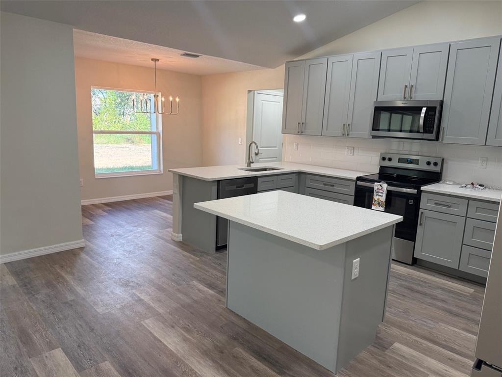A kitchen features gray cabinets, white countertops, a center island, and wood-look flooring — 13465 CANYON SWALLOW ROAD, WEEKI WACHEE, FL
