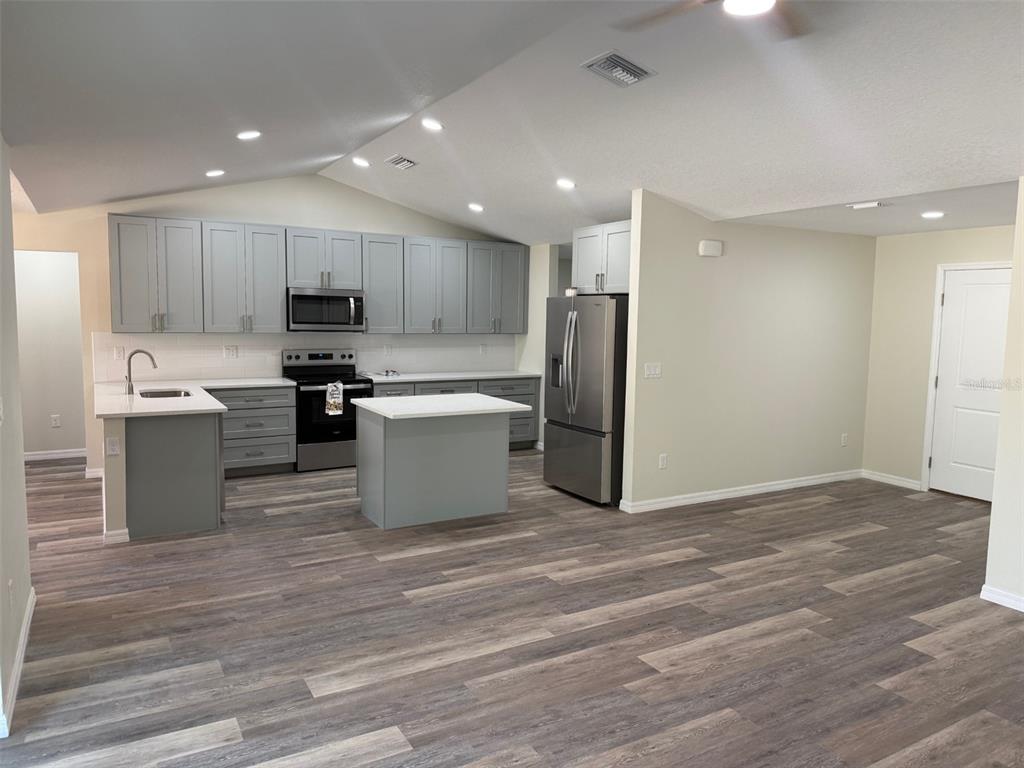 A kitchen with gray cabinets, stainless steel appliances, and a center island on wood flooring — 13465 CANYON SWALLOW ROAD, WEEKI WACHEE, FL
