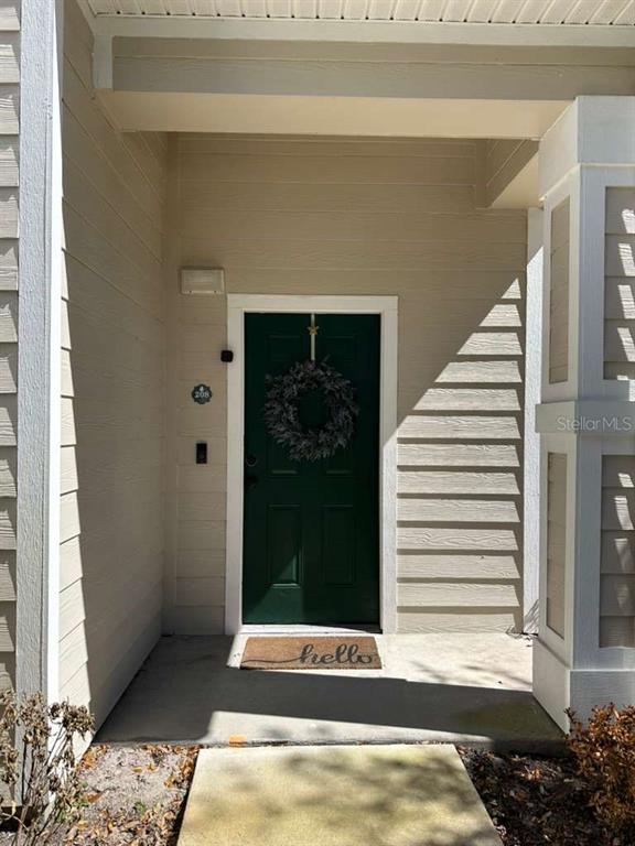 A front entryway features a dark green door with a wreath and a hello doormat — 225 SOUTHERN PECAN CIRCLE UNIT 208, WINTER GARDEN, FL