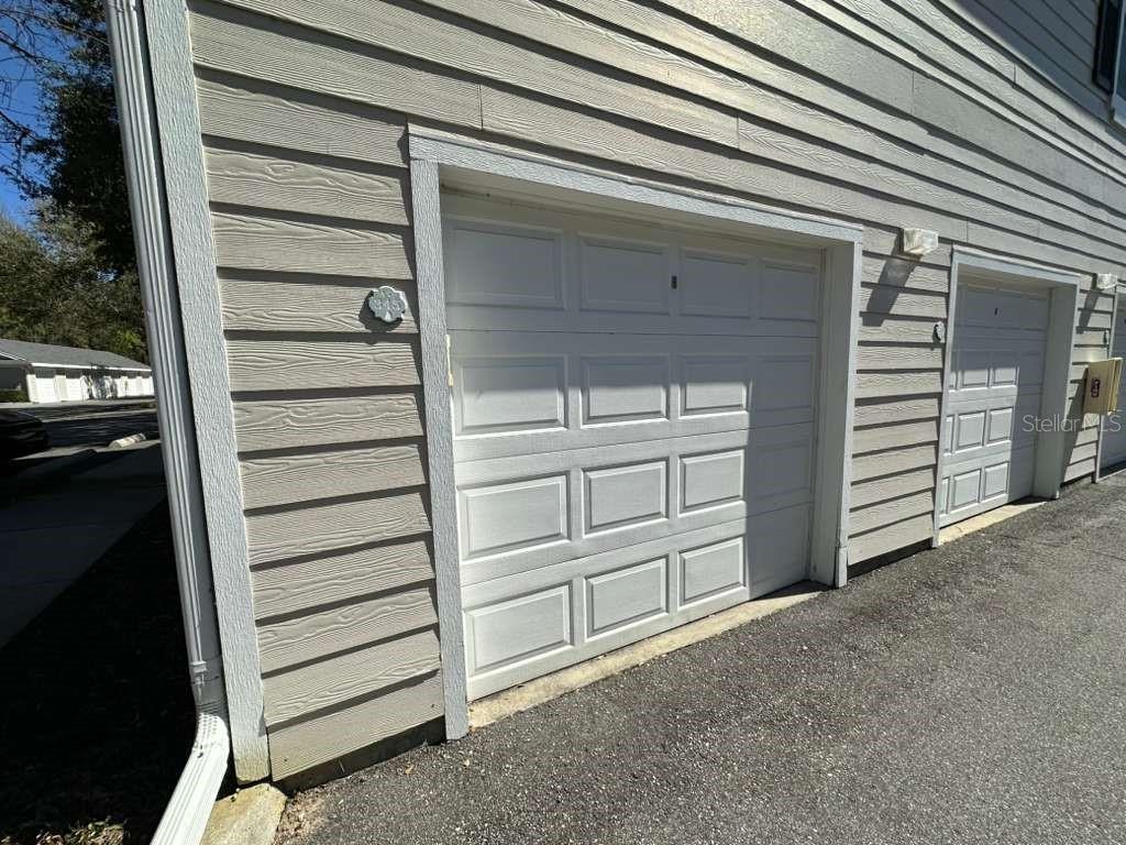 A beige-sided building exterior features two white garage doors with rectangular panels — 225 SOUTHERN PECAN CIRCLE UNIT 208, WINTER GARDEN, FL