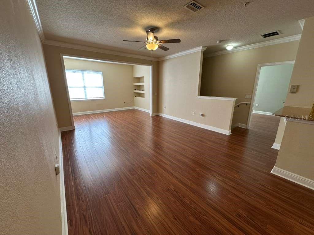 An empty living room features wood-look laminate flooring, a ceiling fan, and a recessed nook — 225 SOUTHERN PECAN CIRCLE UNIT 208, WINTER GARDEN, FL