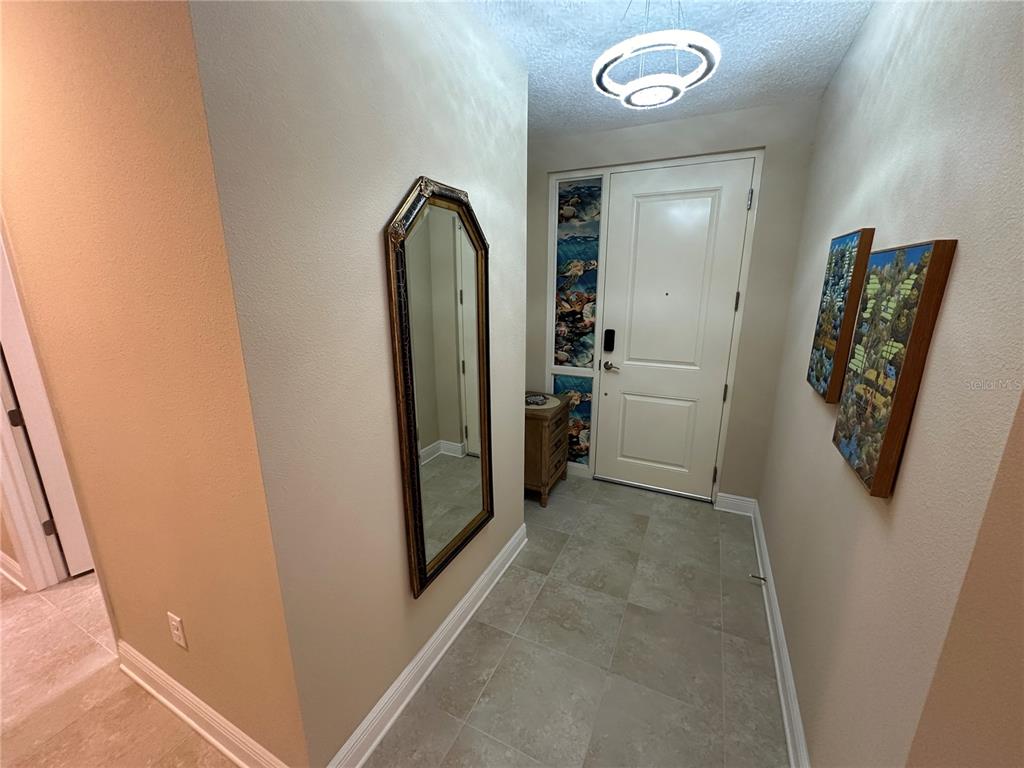 An entryway features a tiled floor, a wall mirror, a front door, and wall art — 3412 79TH STREET CIRCLE W UNIT 103, BRADENTON, FL