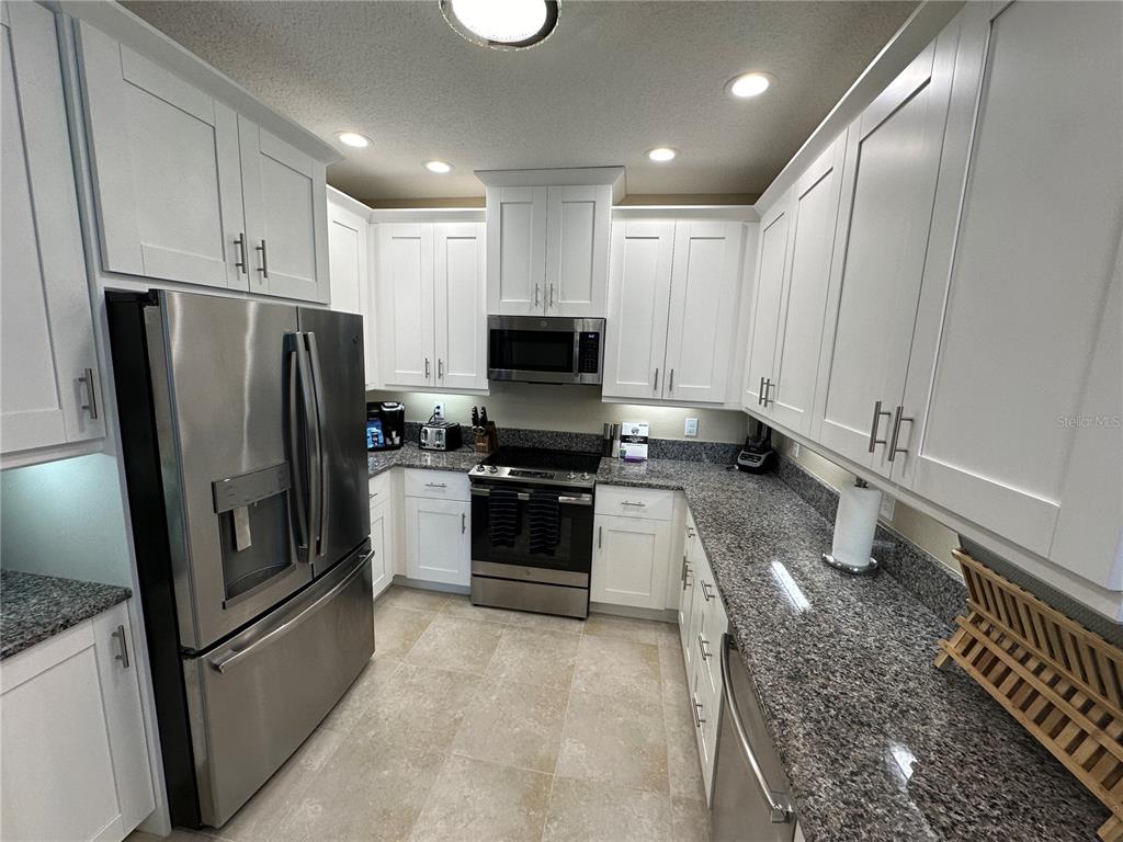 A kitchen features white cabinets, stainless steel appliances, and granite countertops — 3412 79TH STREET CIRCLE W UNIT 103, BRADENTON, FL