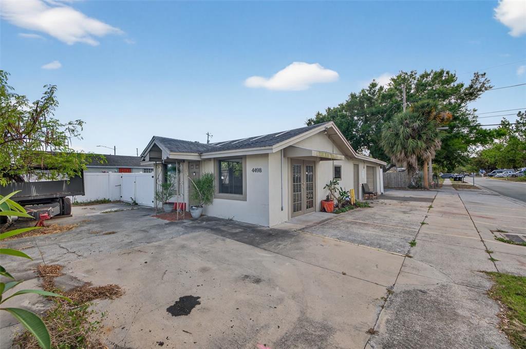 A single-story commercial building with a concrete parking lot and a white fence — 4498 49TH STREET N, ST PETERSBURG, FL