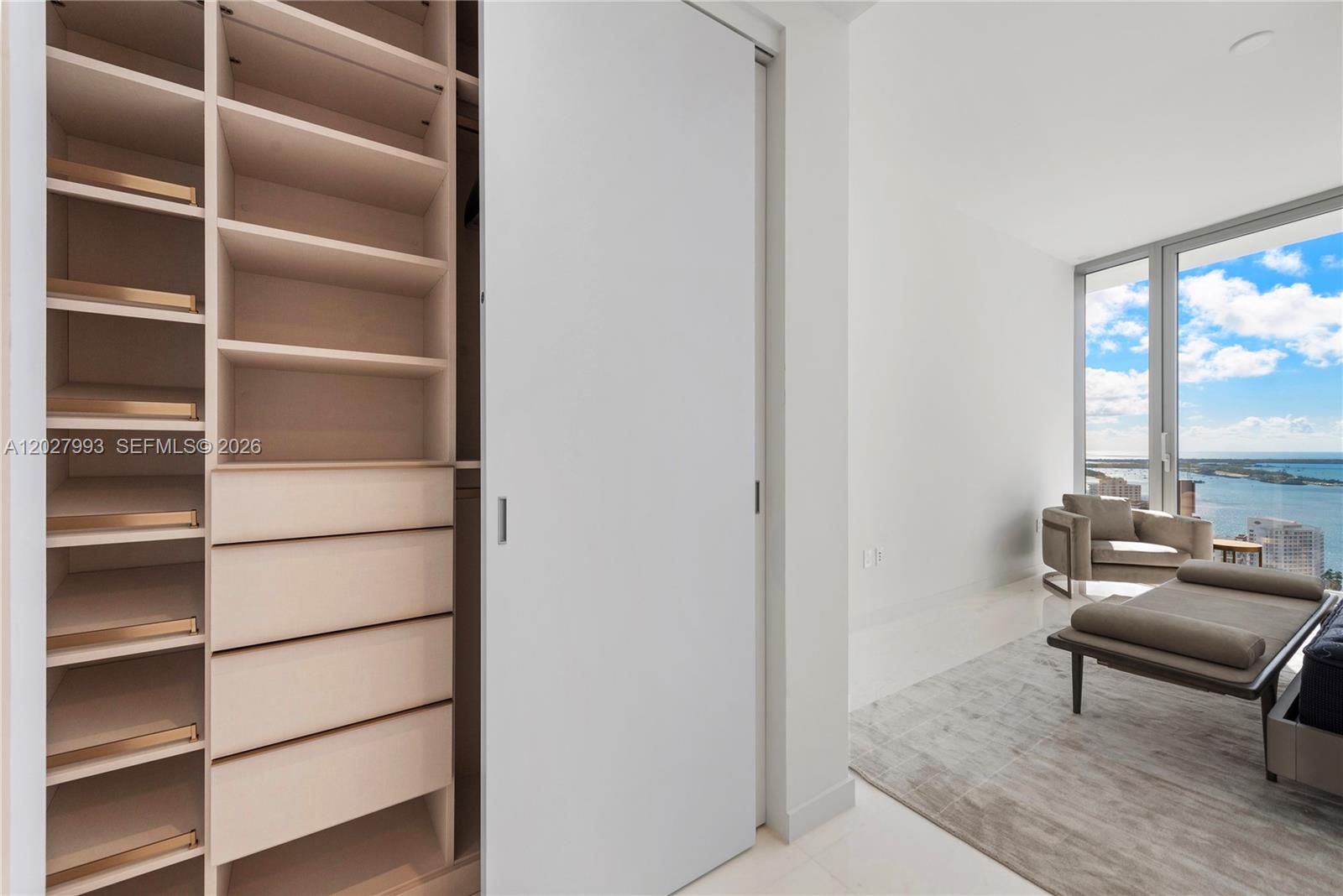 A modern room features a built-in closet with drawers and shelves beside a floor-to-ceiling window — 300 Biscayne Boulevard Way # 3905W, Miami FL 33131, MIAMI, FL