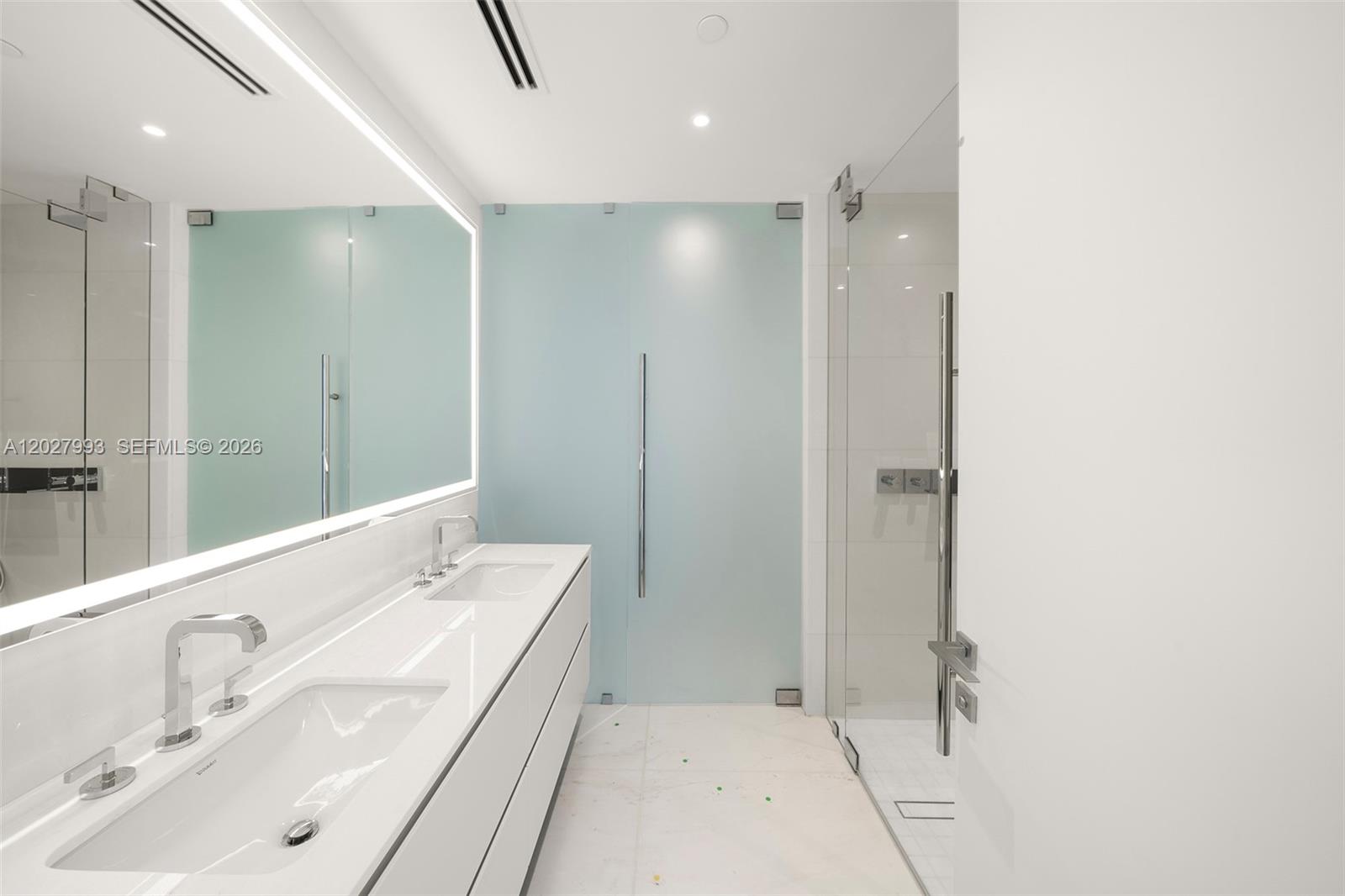 A modern bathroom features a double vanity, a large backlit mirror, and a glass shower — 300 Biscayne Boulevard Way # 3905W, Miami FL 33131, MIAMI, FL