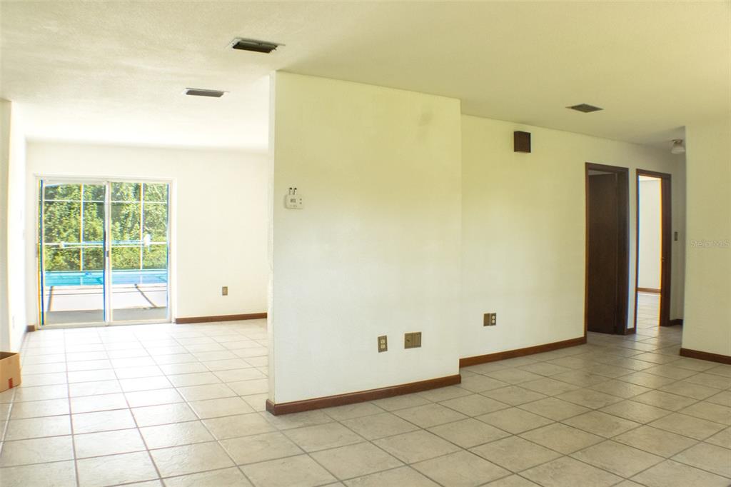 An interior view of a tiled living area featuring a central wall and sliding glass doors — 111 HIGHLAND STREET, ORANGE CITY, FL