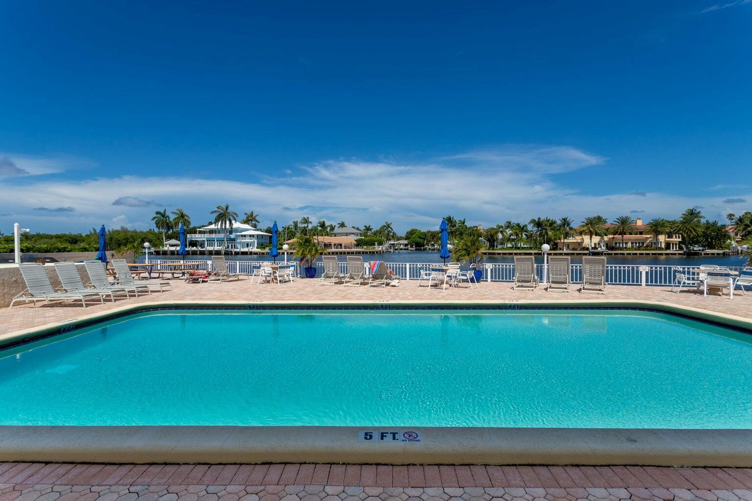 An aerial view of a swimming pool on a patio overlooking a canal and houses — 650 Snug Harbor Drive # G310, Boynton Beach FL 33435, BOYNTON BEACH, FL