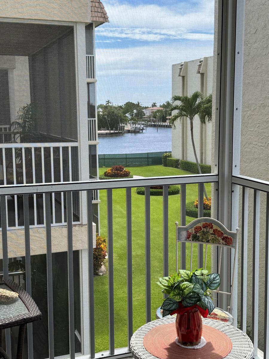 A screened-in balcony overlooks a grassy lawn, a canal with boats, and neighboring apartment buildings — 650 Snug Harbor Drive # G310, Boynton Beach FL 33435, BOYNTON BEACH, FL