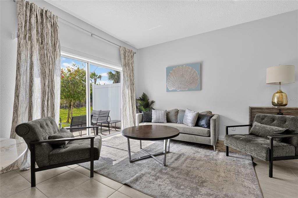 A living room features a sofa, two armchairs, a coffee table, and a sliding glass door — 3023 NOVARA LANE, BRADENTON, FL