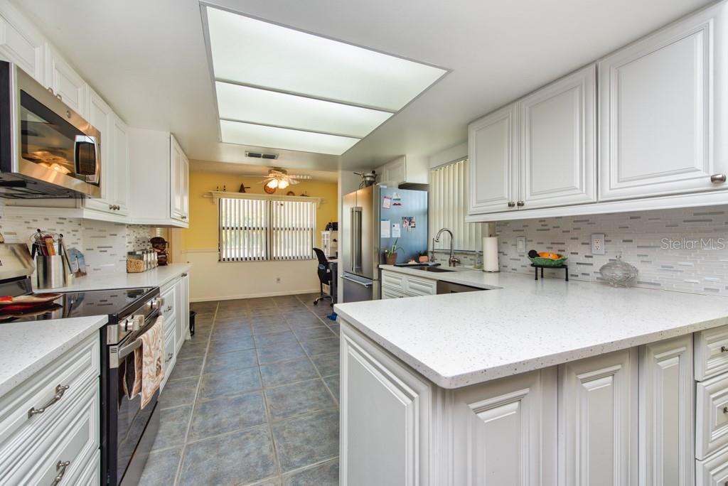 A kitchen with white cabinets, light countertops, a tiled backsplash, and gray floor tiles — 1605 LELAND DRIVE, SUN CITY CENTER, FL