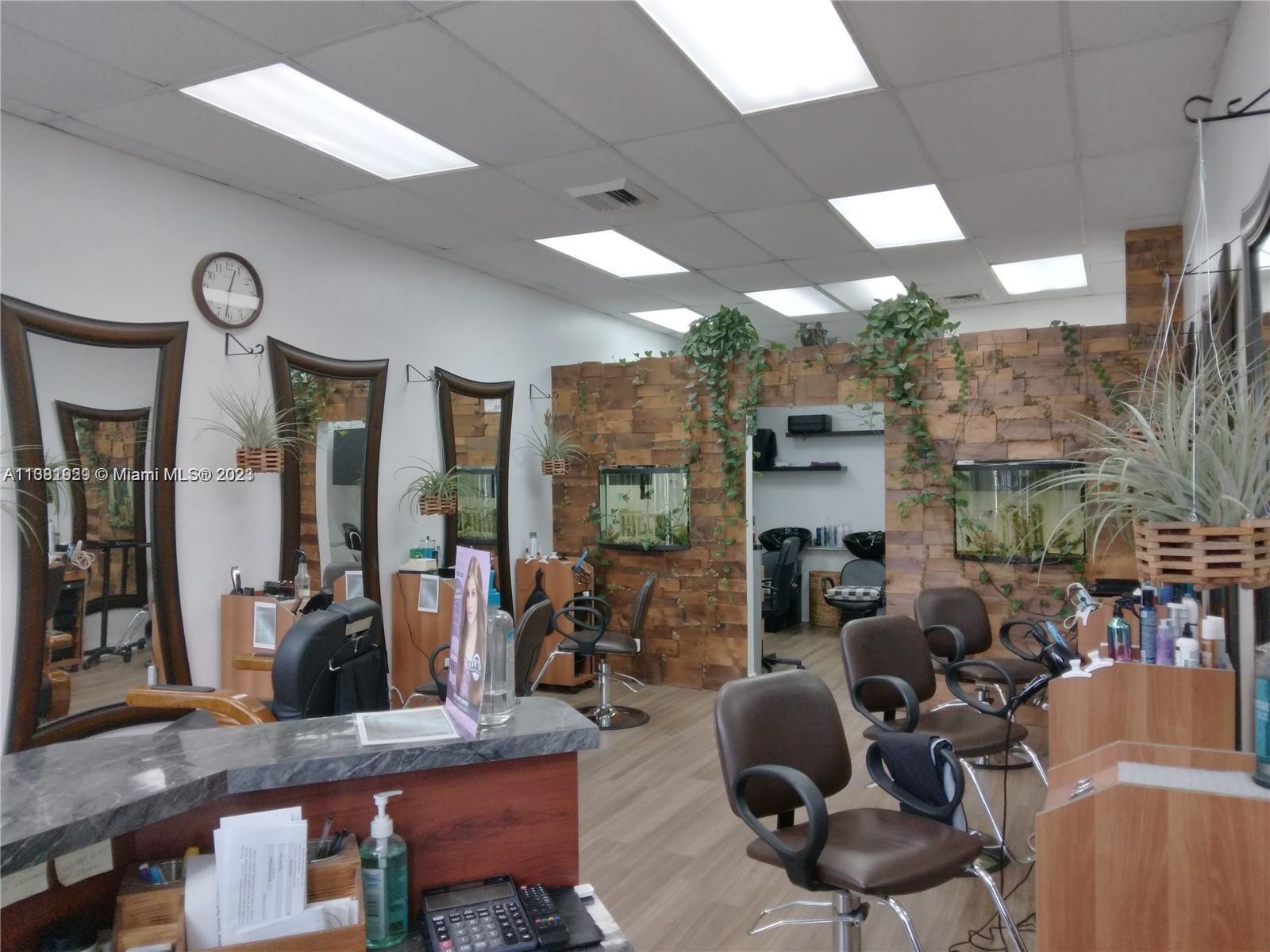 A hair salon features multiple styling stations, wood-paneled walls with integrated aquariums, and hanging plants — 1801 S Ocean Dr, Hallandale Beach FL 33009, HALLANDALE BEACH, FL