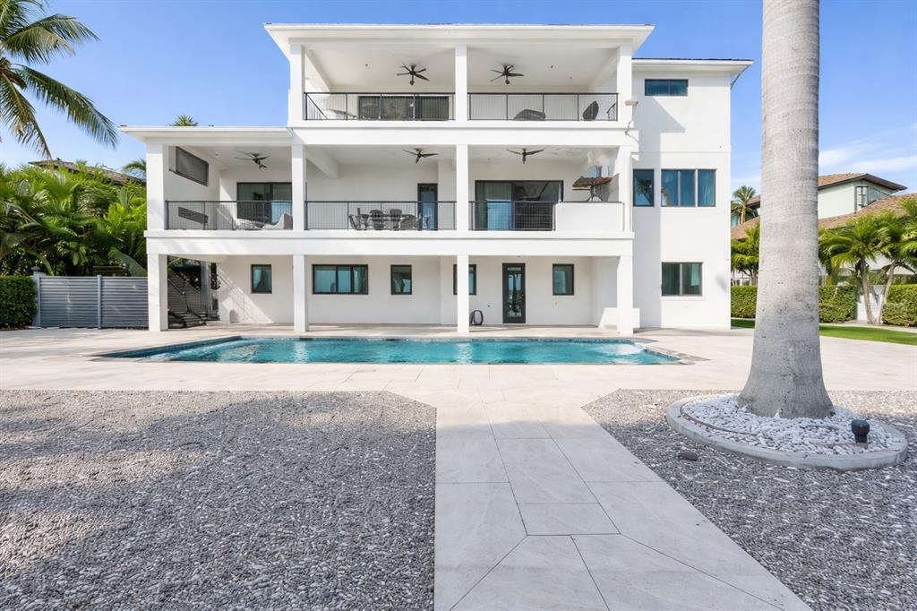 A three-story white house features stacked balconies, a swimming pool, and a gravel yard — 7801 9TH AVENUE S, ST PETERSBURG, FL