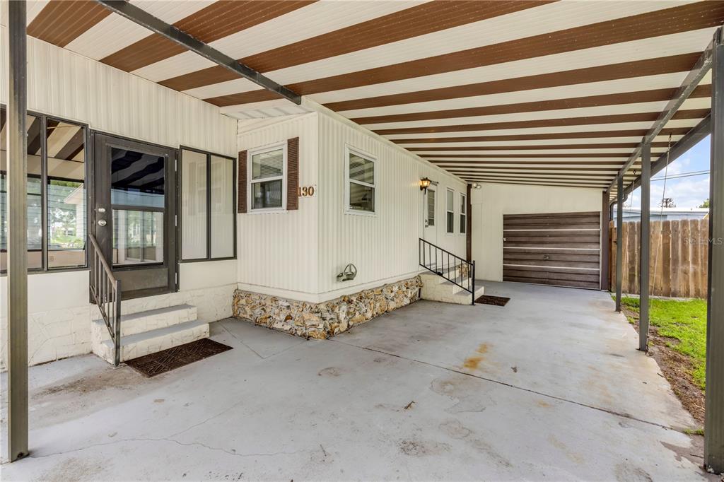 A mobile home exterior features a covered carport, concrete driveway, and two sets of stairs — 130 PINE STREET, EDGEWATER, FL