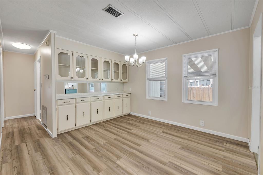 A dining room with light wood-look flooring, beige walls, white cabinetry, and a chandelier — 130 PINE STREET, EDGEWATER, FL