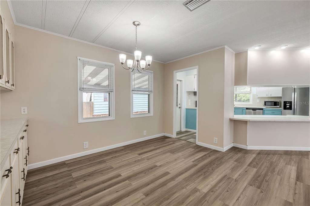 A dining room with wood-look flooring, a chandelier, and an opening to the kitchen — 130 PINE STREET, EDGEWATER, FL