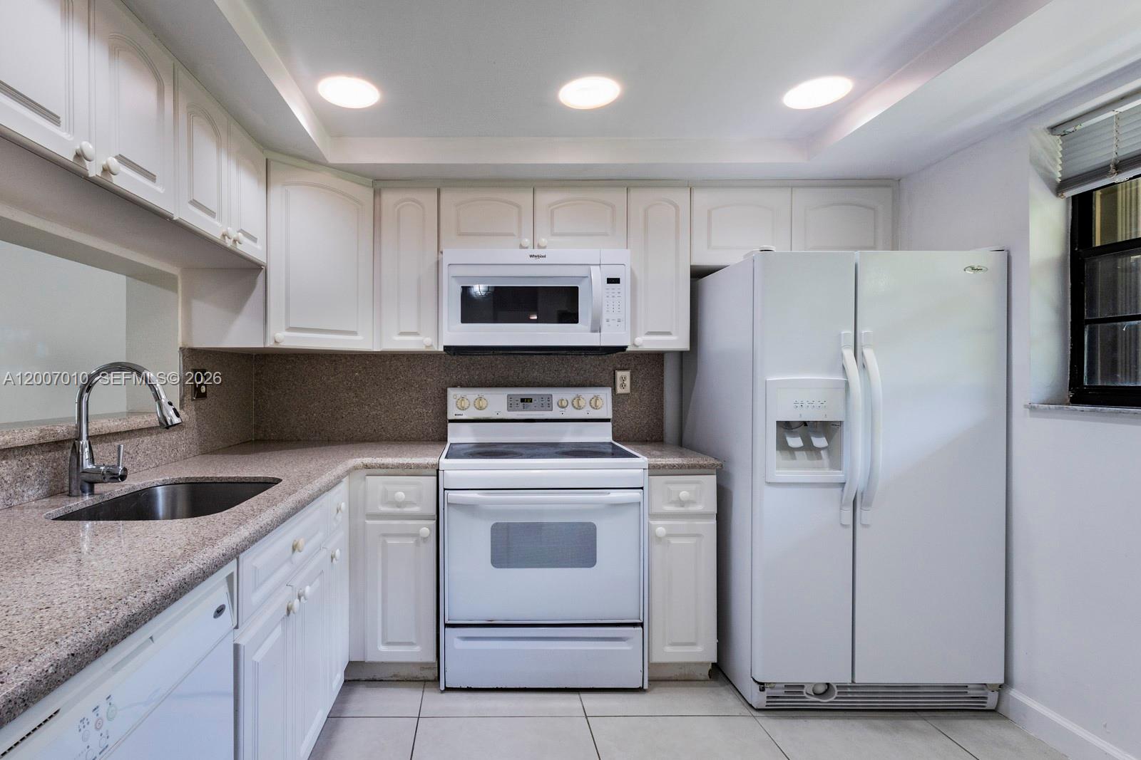 A kitchen features white cabinets, white appliances, and speckled granite countertops — 10855 SW 112th Ave # 211, Miami FL 33176, MIAMI, FL