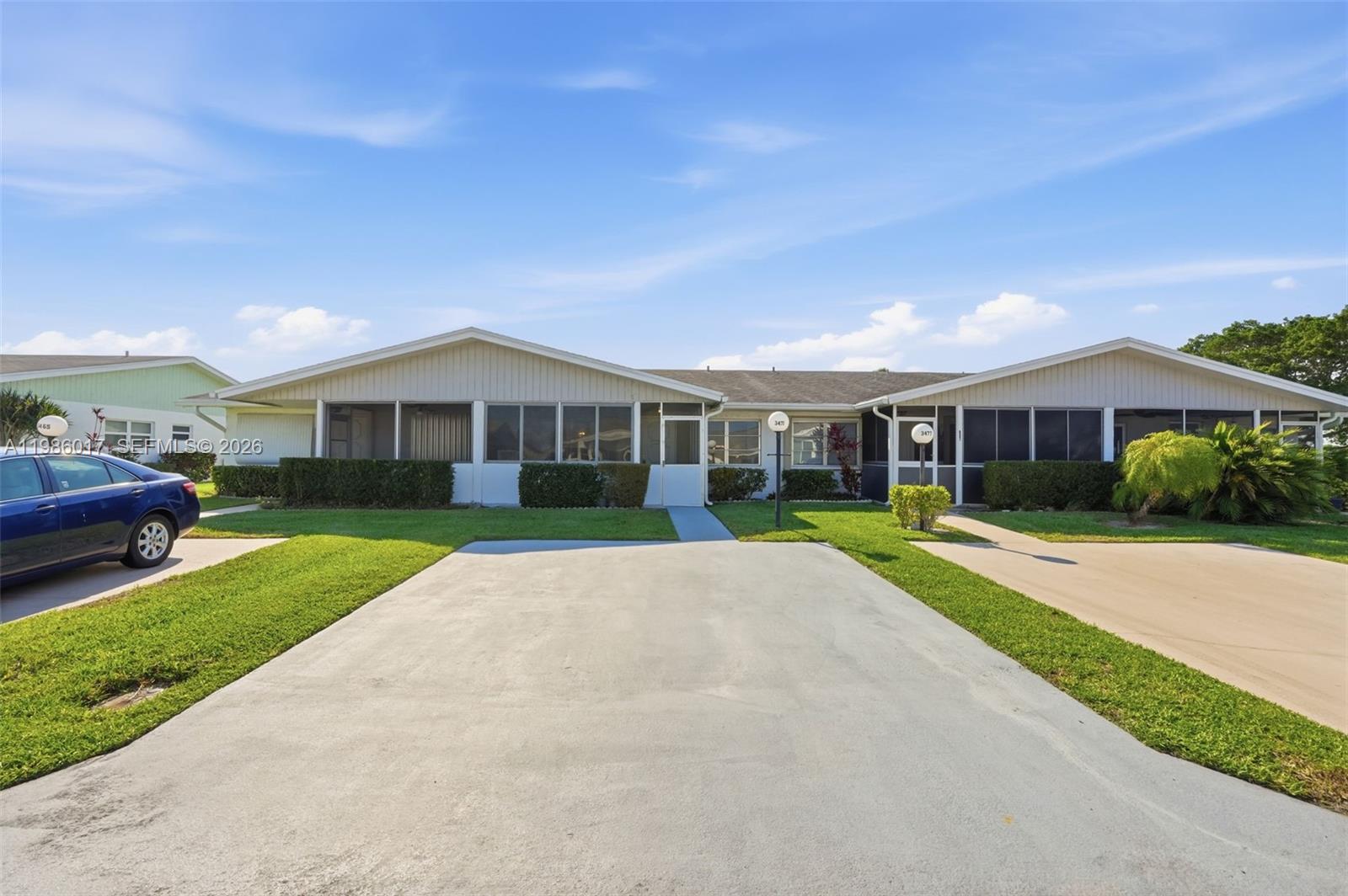 A single-story duplex with screened-in porches and concrete driveways under a blue sky — 3471 Christopher St, West Palm Beach FL 33417, WEST PALM BEACH, FL