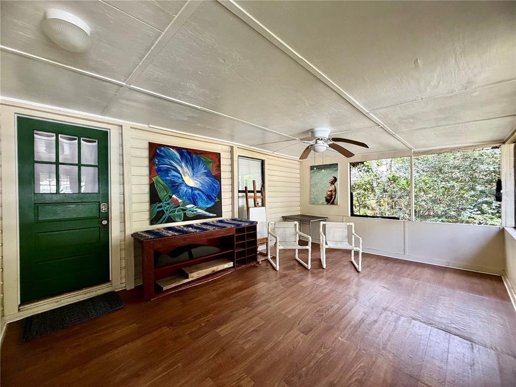 A sunroom features wood-look flooring, a green door, a ceiling fan, and large screened windows — 25140 NE 133RD STREET, FORT MC COY, FL