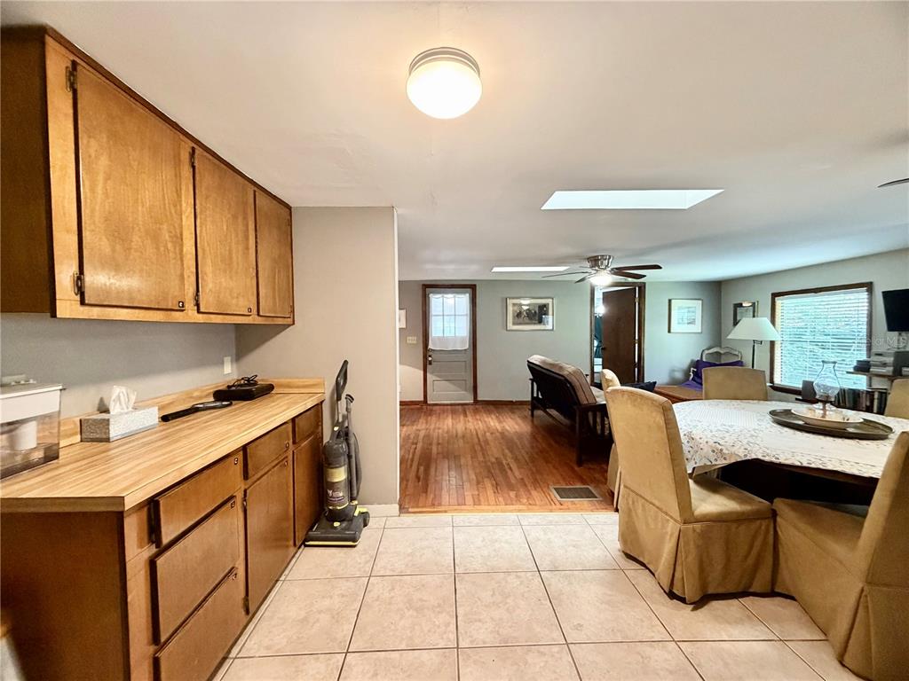 A kitchen with wood cabinets and tile flooring opens into a living area with hardwood floors — 25140 NE 133RD STREET, FORT MC COY, FL