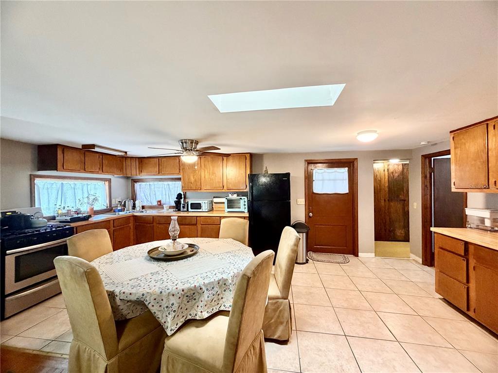 A kitchen features wood cabinetry, a dining table with chairs, and a tiled floor — 25140 NE 133RD STREET, FORT MC COY, FL
