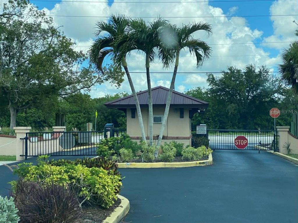 A gated entrance features a small guardhouse, palm trees, and a stop sign — 23465 HARBORVIEW ROAD UNIT 245, PUNTA GORDA, FL