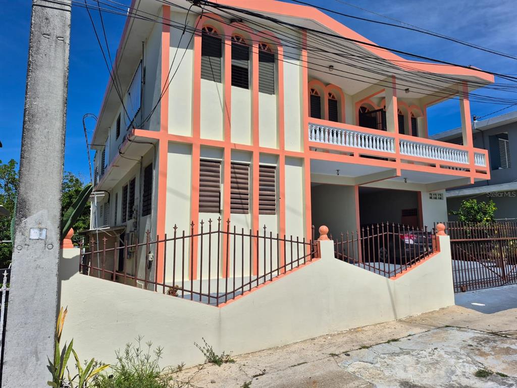 A two-story house with peach-colored trim, a balcony, and a metal fence in front — #55A CALLE JOSÉ HERNANDEZ, ISABELA, PR