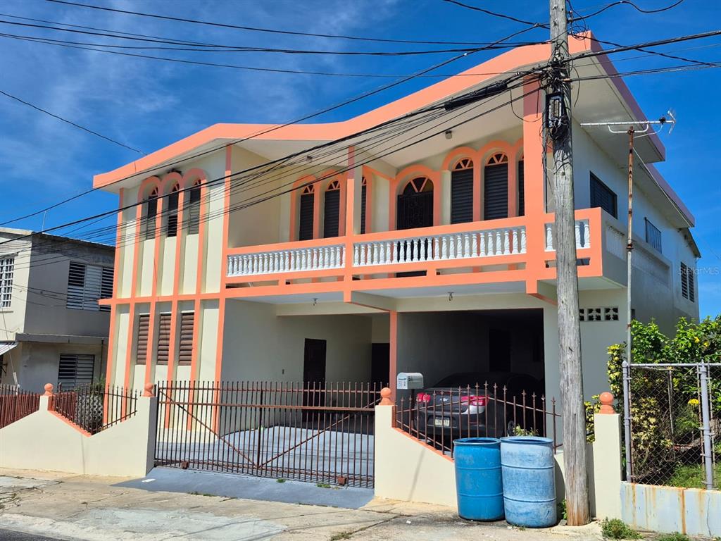 A two-story house with a peach-colored exterior, a balcony, and a gated driveway — #55A CALLE JOSÉ HERNANDEZ, ISABELA, PR