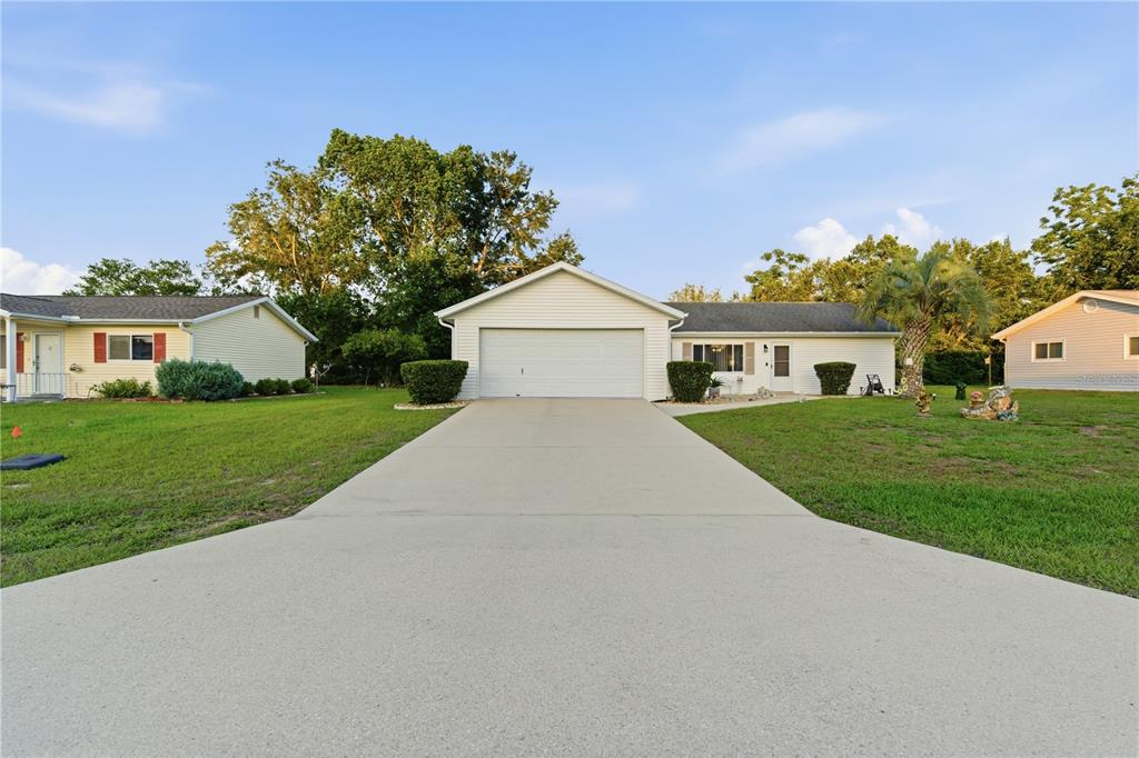 A single-story house with a white garage and a concrete driveway under a blue sky — 11241 SW 77TH COURT, OCALA, FL