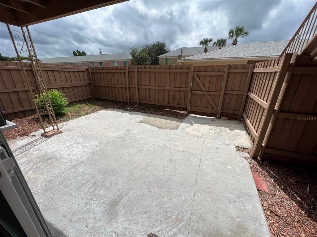 A concrete patio enclosed by a wooden fence with a gate and a metal support — 524 GEORGETOWN DRIVE UNIT B, CASSELBERRY, FL