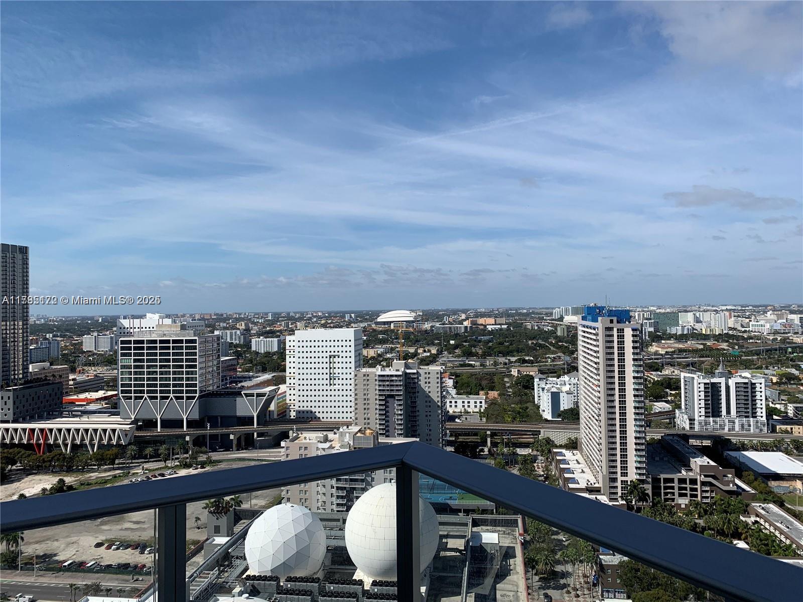 High-angle view of a city skyline from a balcony with a dark metal railing — 851 NE 1st Ave # 3002, Miami FL 33132, MIAMI, FL