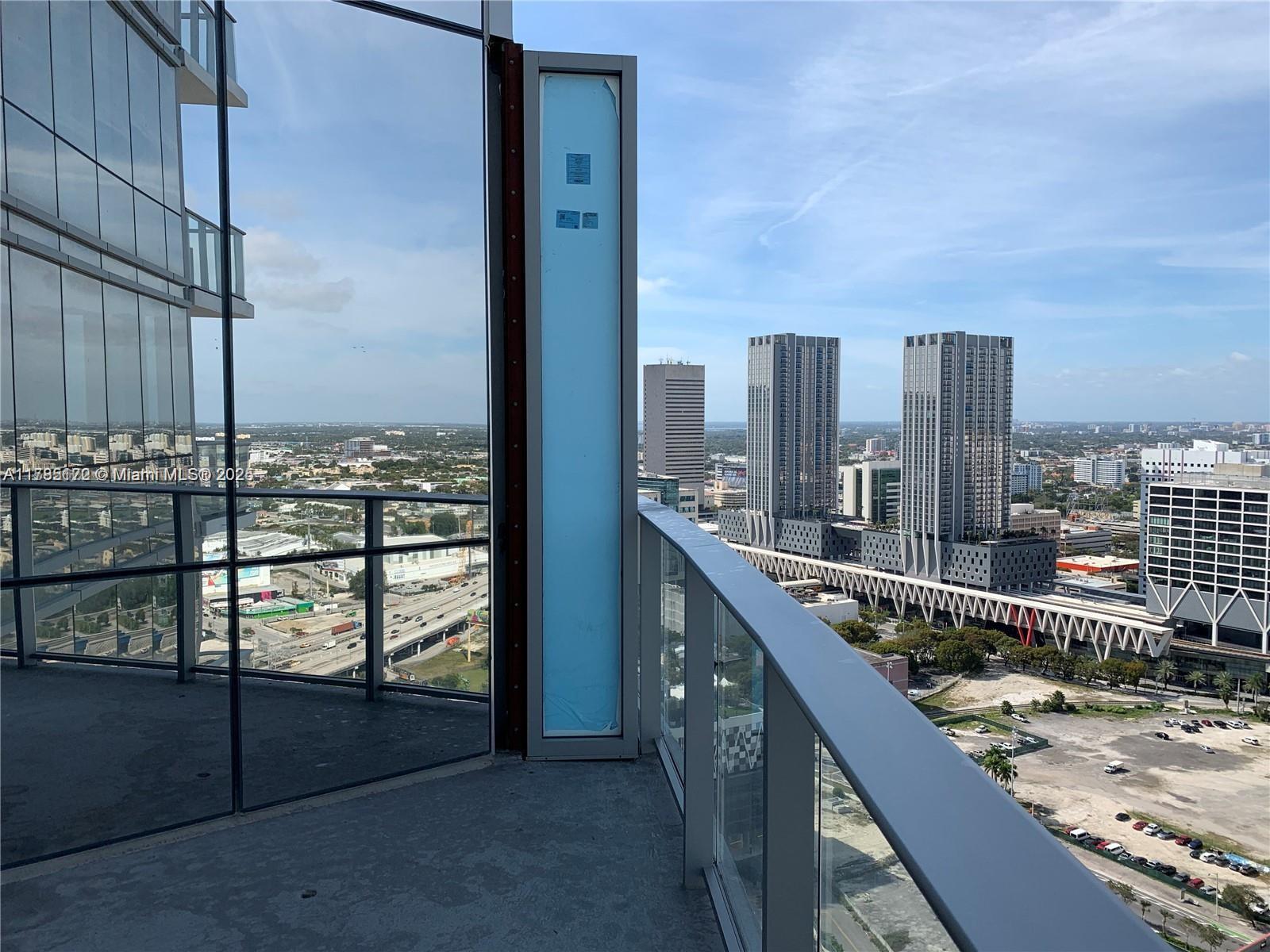 A high-rise balcony with glass railings overlooks a city skyline and highway — 851 NE 1st Ave # 3002, Miami FL 33132, MIAMI, FL