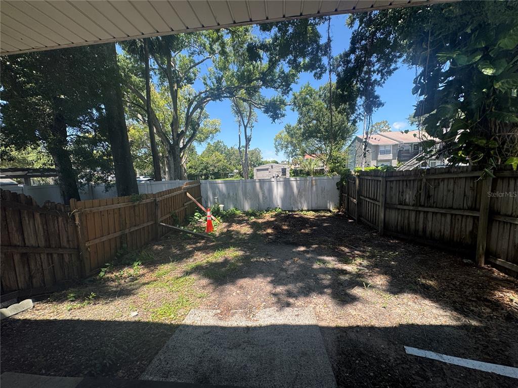 A small backyard features a dirt patch, a white vinyl fence, and wooden side fencing — 3607 W IDLEWILD AVENUE UNIT 501, TAMPA, FL