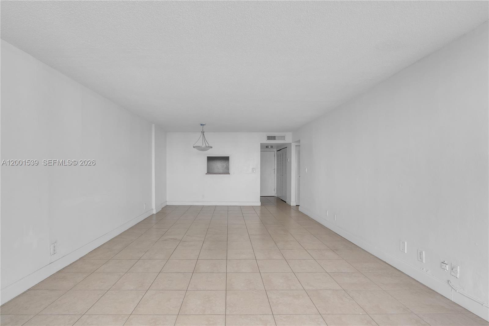 An empty, white-walled room features beige tile flooring and a small pass-through window — 9143 SW 77th Ave # B710, Miami FL 33156, MIAMI, FL