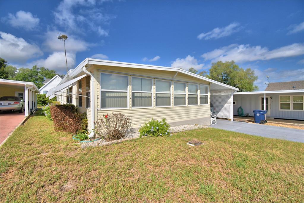 A light yellow mobile home with a large sunroom and an attached carport — 169 PARADISE LANE, AUBURNDALE, FL