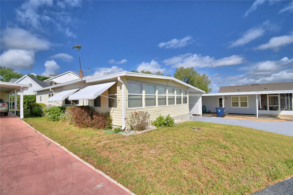 A light-colored mobile home with a screened-in porch and a red driveway — 169 PARADISE LANE, AUBURNDALE, FL