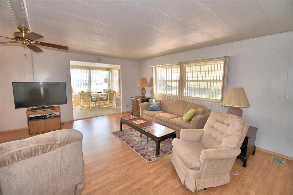 A living room with light wood flooring, a beige sofa, and a matching armchair — 169 PARADISE LANE, AUBURNDALE, FL