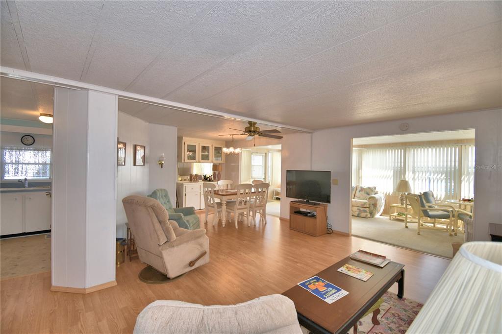 An open-concept living and dining area features light wood flooring and a ceiling fan — 169 PARADISE LANE, AUBURNDALE, FL