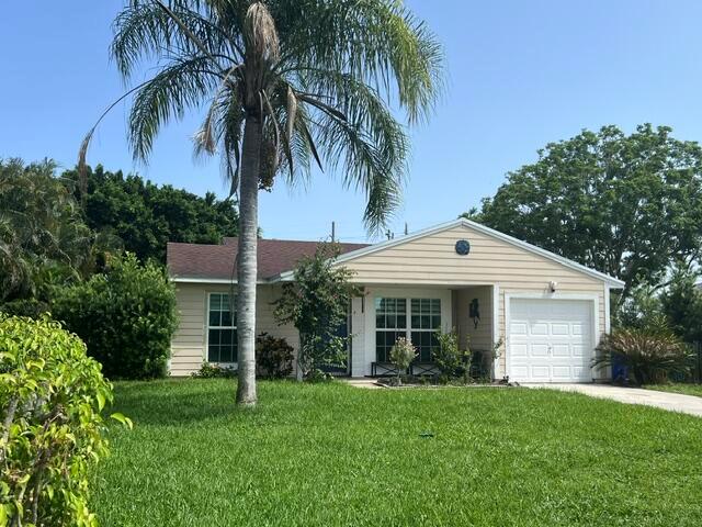A single-story house with beige siding, a white garage door, and a tall palm tree — 9145 Chrysanthemum Drive, Boynton Beach FL 33472, BOYNTON BEACH, FL