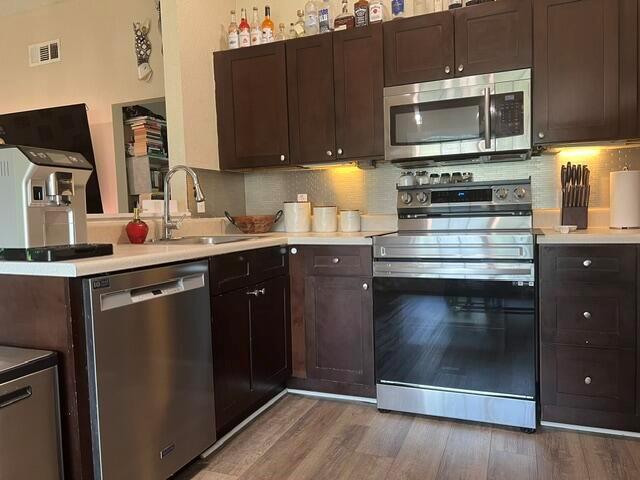 A kitchen features dark wood cabinets, stainless steel appliances, and light-colored countertops — 9145 Chrysanthemum Drive, Boynton Beach FL 33472, BOYNTON BEACH, FL