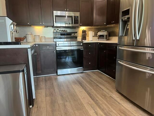 A kitchen features dark wood cabinets, stainless steel appliances, and light wood-look flooring — 9145 Chrysanthemum Drive, Boynton Beach FL 33472, BOYNTON BEACH, FL