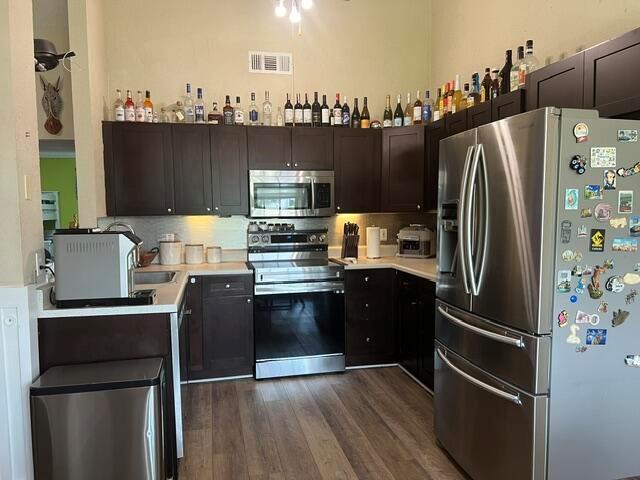 A kitchen features dark wood cabinets, stainless steel appliances, and a collection of liquor bottles — 9145 Chrysanthemum Drive, Boynton Beach FL 33472, BOYNTON BEACH, FL