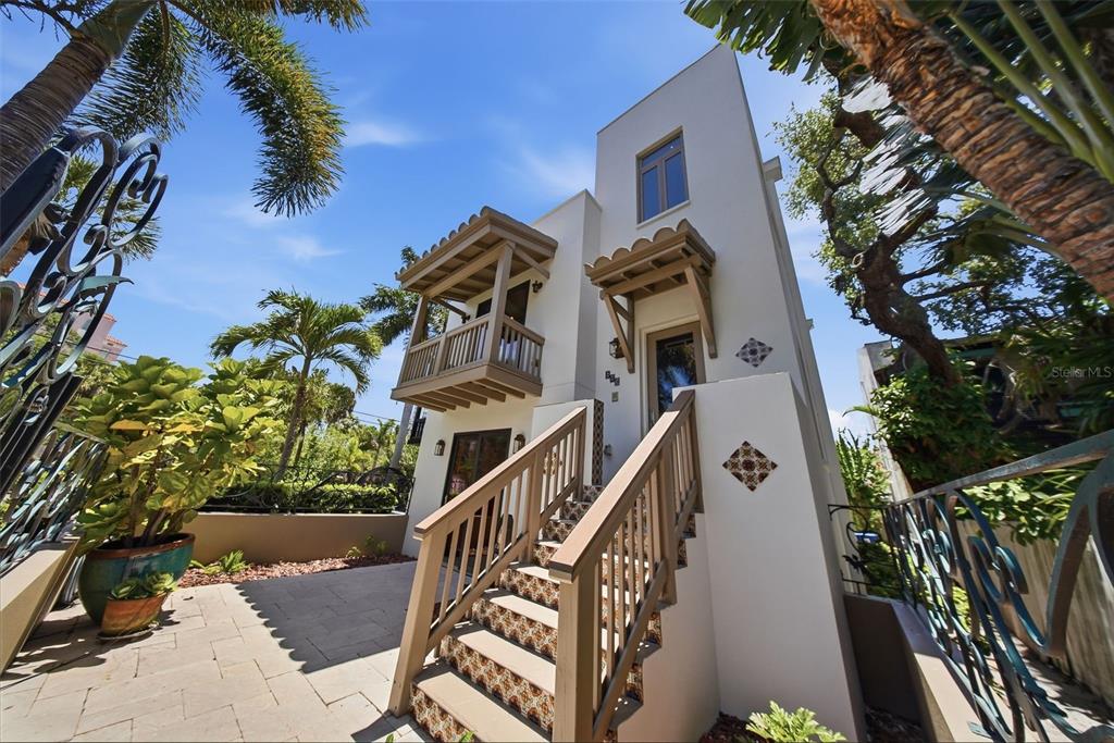 A white multi-story house features a wooden staircase with patterned risers and a balcony — 650 BEACH DRIVE NE, ST PETERSBURG, FL