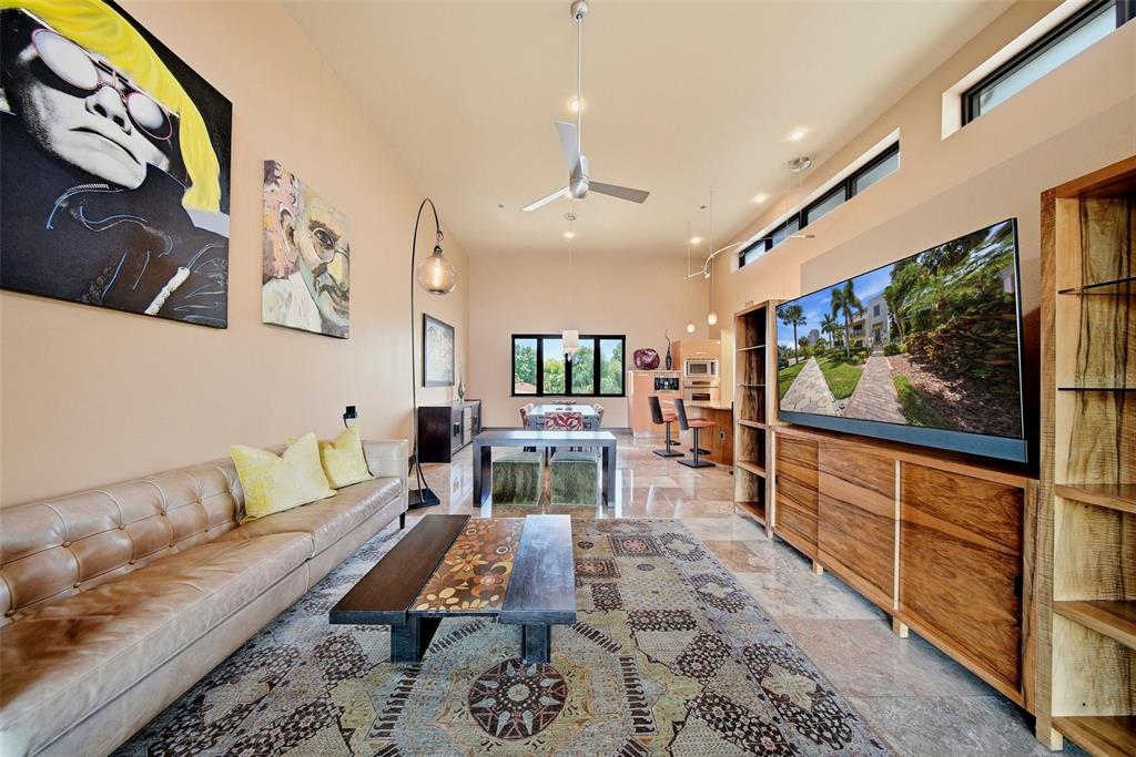 A living room features a leather sofa, a patterned rug, and a large wall-mounted television — 650 BEACH DRIVE NE, ST PETERSBURG, FL