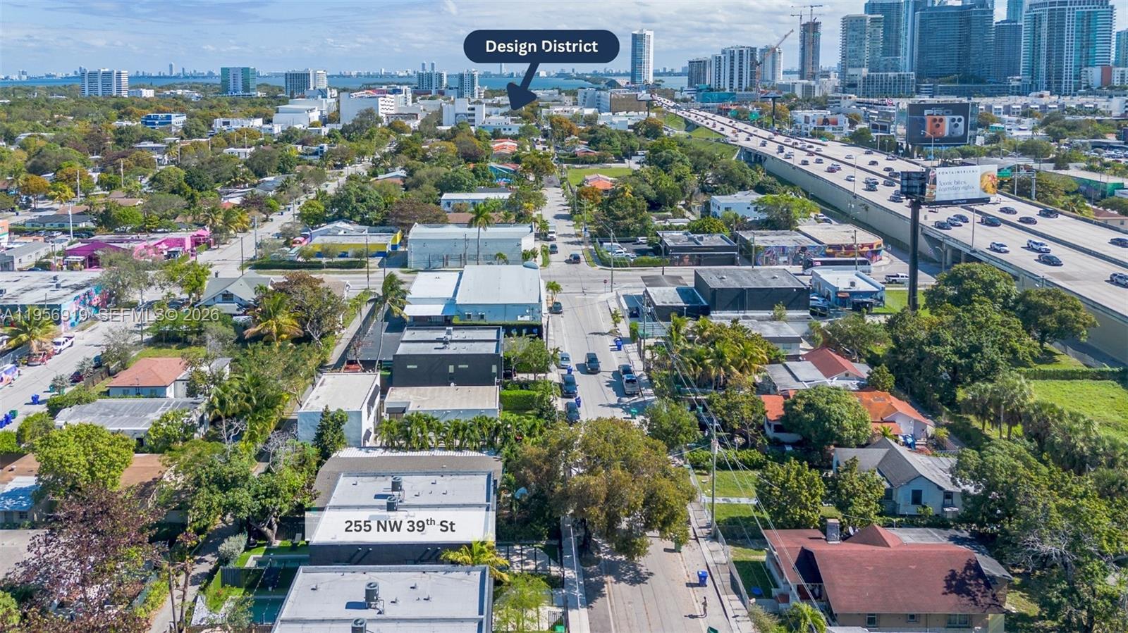 An aerial view shows a street with low-rise buildings, lush trees, and a nearby highway — 255 NW 39th St, Miami FL 33127, MIAMI, FL