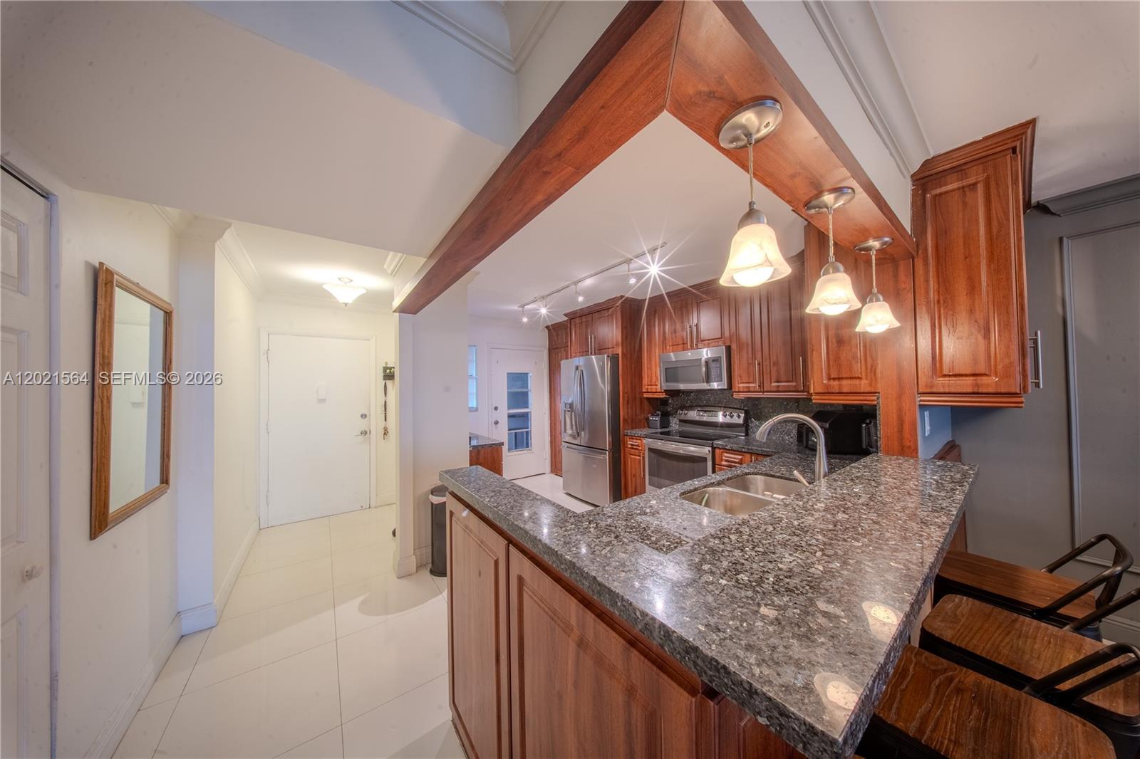 A kitchen features wood cabinets, granite countertops, a breakfast bar, and stainless steel appliances — 1660 NE 191st St # 1, Miami FL 33179, MIAMI, FL