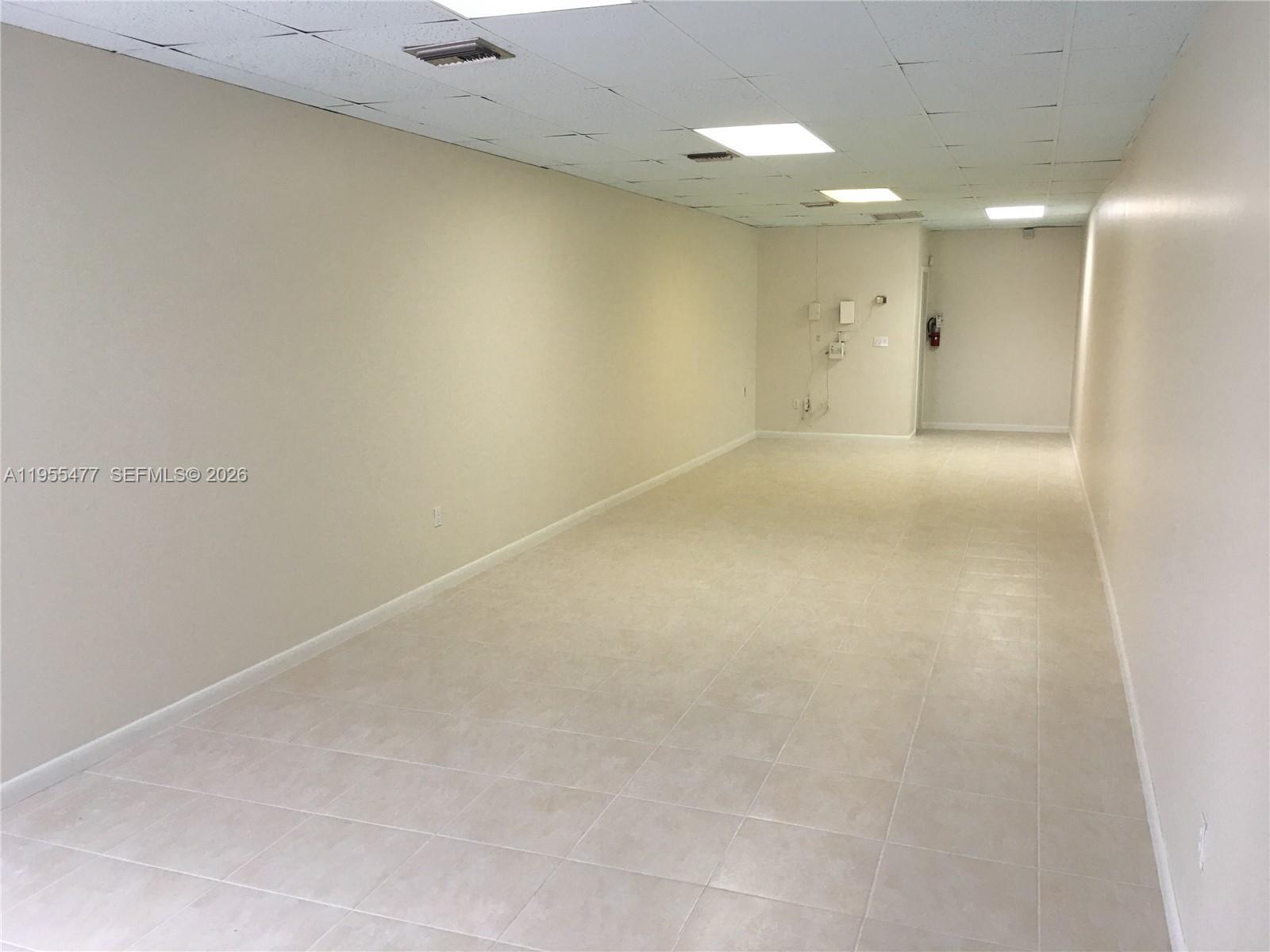 An empty, rectangular commercial space features beige walls, tiled flooring, and a drop ceiling — 10509 SW 40th St # 10509, Miami FL 33165, MIAMI, FL